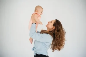Smiling adult woman holding her newborn baby, representing successful IVF with donor eggs